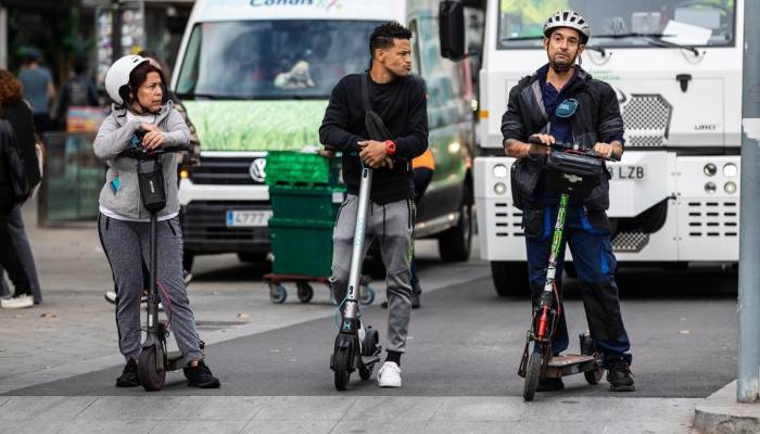 Tres patinadores aguardan el momento de avanzar, en un cruce de Barcelona